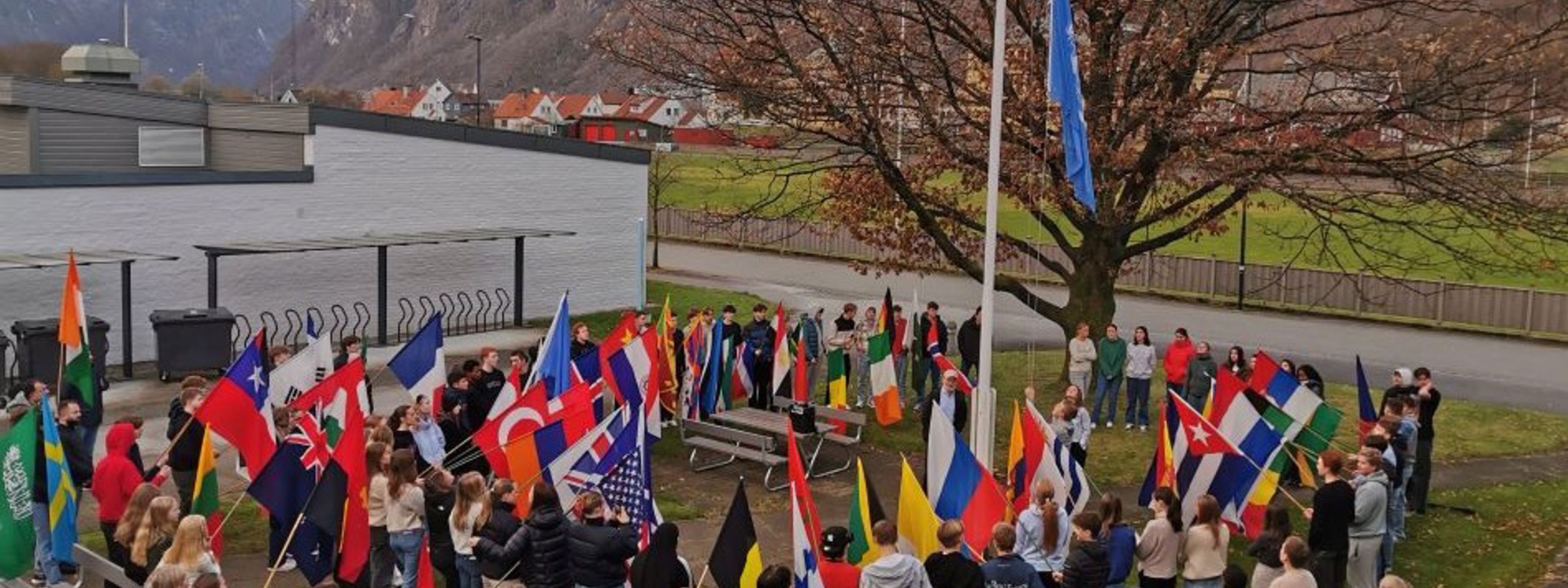 Elevar heiser FN flagget og står rundt flaggstanga med flagg frå heile verda
